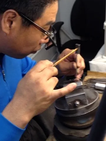 A jeweler carefully working on a small piece at a bench